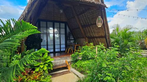 a house with a thatched roof with a bench in front at Ten Foundations in Balayan