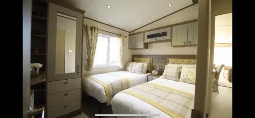 a small bedroom with two beds and a window at Fabulous seaside caravan getway at Cayton Bay in Scarborough