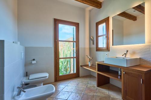 a bathroom with a sink and a toilet and a window at Finca Hort Can Veritat in Cala Ferrera