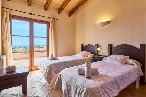 a bedroom with two beds and a large window at Finca Hort Can Veritat in Cala Ferrera
