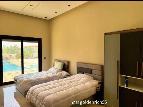 two beds in a room with a pool at Reef Golden Resort شاليه الريف الذهبي in Qaryat ash Shamālī