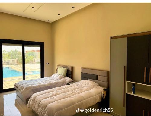 two beds in a room with a pool at Reef Golden Resort شاليه الريف الذهبي in Qaryat ash Shamālī