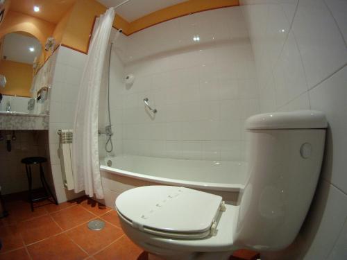 a white toilet sitting next to a bath tub in a bathroom at Hotel Rural Cuartamenteru in Po