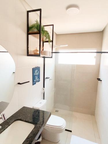 a bathroom with a sink and a toilet and a mirror at Condomínio Vila do Mar - Apartamento 3 quartos in Luis Correia