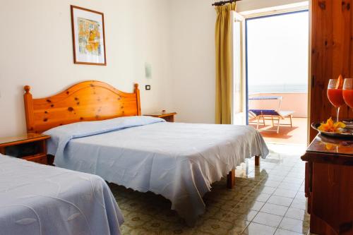 a bedroom with two beds and a large window at Hotel Regina del Mare in Ischia