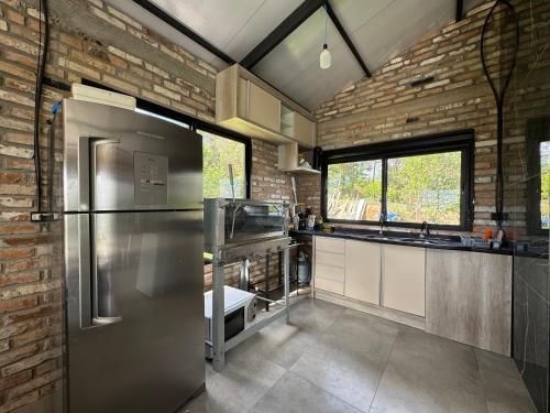 eine Küche mit einem Kühlschrank aus Edelstahl und einer Ziegelwand in der Unterkunft Pico da neblina in Farroupilha