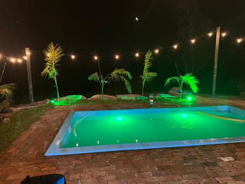 ein Swimmingpool bei Nacht mit Lichtern und Palmen in der Unterkunft Pico da neblina in Farroupilha
