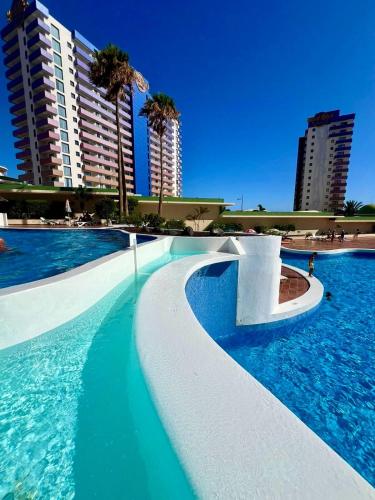 a swimming pool with blue water and tall buildings at Bonito in Adeje
