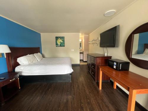 a hotel room with a bed and a flat screen tv at Capitol Inn by Belvilla Richmond Airport VA in Sandston