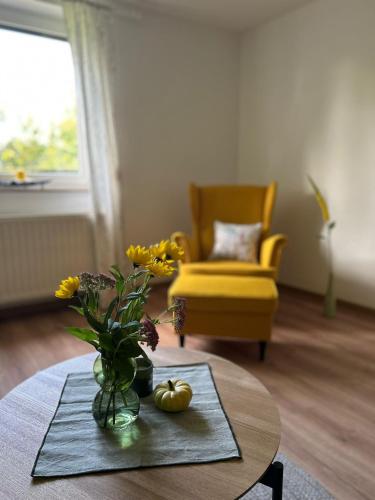 a living room with a table and a yellow chair at Ferienwohnung Dorfliebe in Oettersdorf