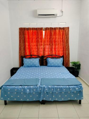 a bedroom with a blue bed with a red curtain at Aahana Homestay in Merlimau