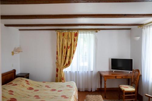 a bedroom with a bed and a desk with a television at La Ferme du Franz in Diefmatten