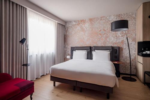 a hotel room with a bed and a red couch at Hôtel LÉONOR the place to live in Strasbourg