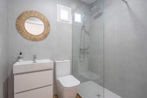 a bathroom with a toilet and a shower and a mirror at Villa Rocio in Chiclana de la Frontera