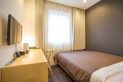 ein Schlafzimmer mit Bett, Schreibtisch und Fenster in der Unterkunft Hotel Asia Center of Japan in Tokio