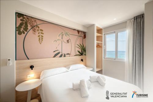 ein Schlafzimmer mit einem weißen Bett und einem Gemälde an der Wand in der Unterkunft Mara Boutique Apartments in Benidorm