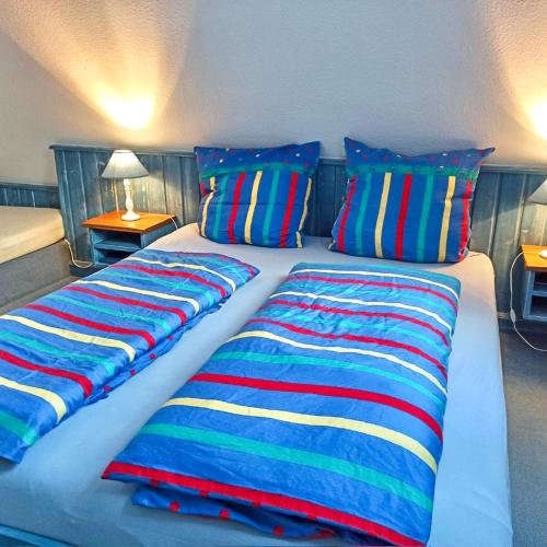 two beds with colorful blankets and pillows in a bedroom at Warfthüs, App 7 in Rantum