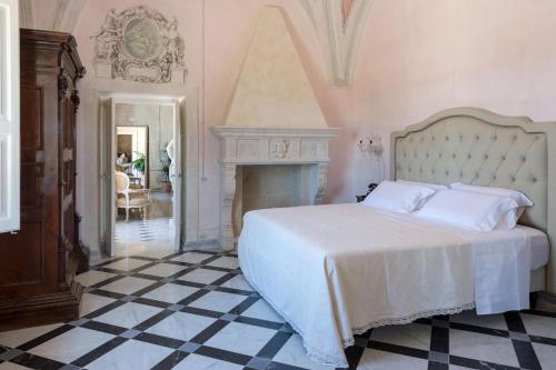 a bedroom with a white bed and a fireplace at Tenuta Mosè Charming House&Relais Gallipoli in Gallipoli