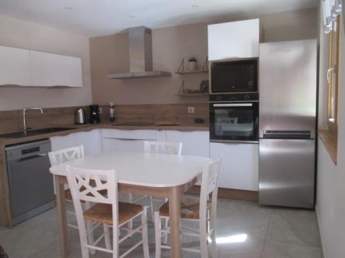 a kitchen with a white table and white chairs at Casabert T2 Glycine Quiet and harmonious in Saint-Martin-de-la-Porte