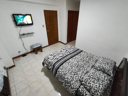 una camera con un letto bianco e nero e una TV di Alta vista Suite a Ciudad Guayana