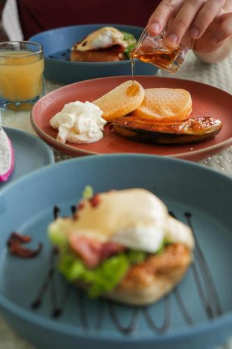 Uma pessoa está colocando molho em um sanduíche que está em um prato. em 500 Rai Floating Resort em Ban Chieo Ko
