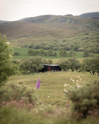 a barn in a field with trees and hills at The Rising in Tongue