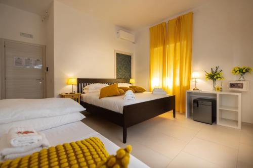 a bedroom with two beds with yellow curtains and a desk at Villa Vera in Salerno