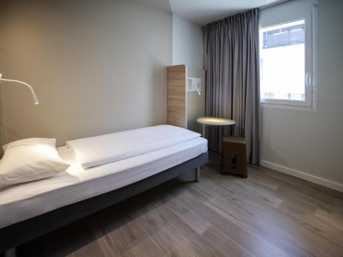 a bedroom with a large bed and a window at ibis budget Fribourg in Fribourg