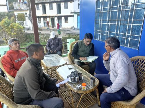 un grupo de hombres sentados alrededor de una mesa en mayur homestay, en Ukhimath