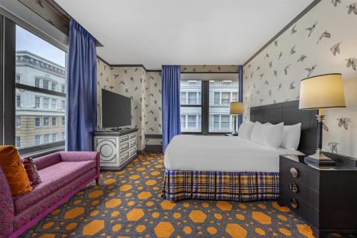 a bedroom with a bed and a couch and a tv at The Royal Sonesta Portland Downtown in Portland