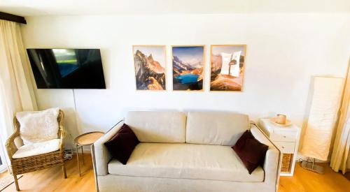 a living room with a white couch and pictures on the wall at Studio Alpenhaus in Bettmeralp