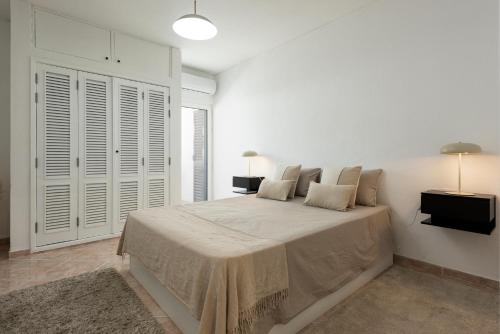 a white bedroom with a large bed and two lamps at NUZZA - Vilamoura Marina with BBQ in Vilamoura