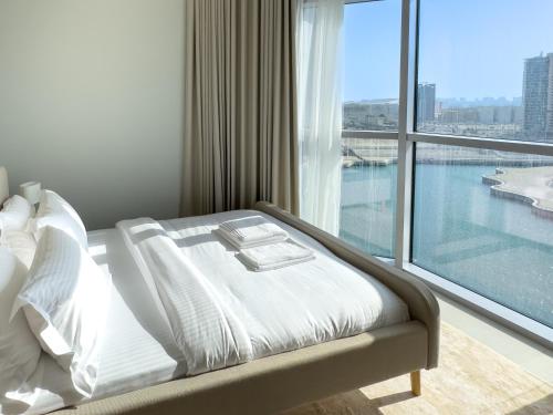 a white bed in a room with a large window at Sea View 2br Luxury Apartment Reem Island Escape in Abu Dhabi