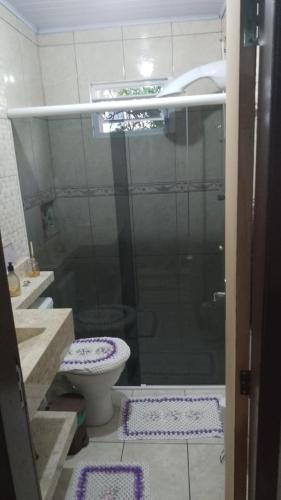 a bathroom with a shower with a toilet and purple rugs at Alberto in Governador Celso Ramos