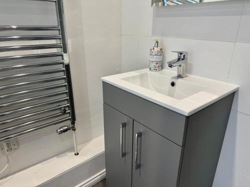 a white bathroom with a sink and a shower at Camellia Cottage With Garden in Bowness-on-Windermere