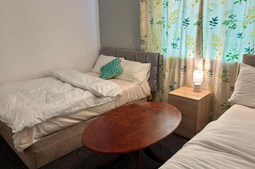 ein kleines Zimmer mit 2 Betten und einem Holztisch in der Unterkunft 2 Bed House-Sleeps 4-Free Parking in Coseley