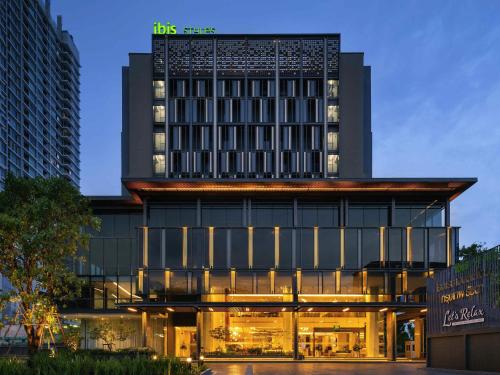 a hotel building with a lit up facade at night at ibis Styles Bangkok Ratchada in Bangkok
