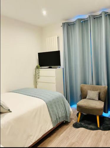 a bedroom with a bed and a chair and a tv at Cozy Private Access Room in Great Bookham