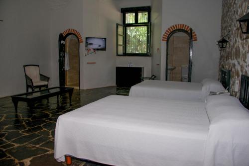 a bedroom with two white beds and a tv at Hotel Hacienda Vista Hermosa in Tequesquitengo