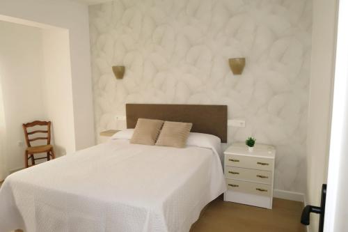 a white bedroom with a white bed and a chair at La Placeta in Vara de Rey
