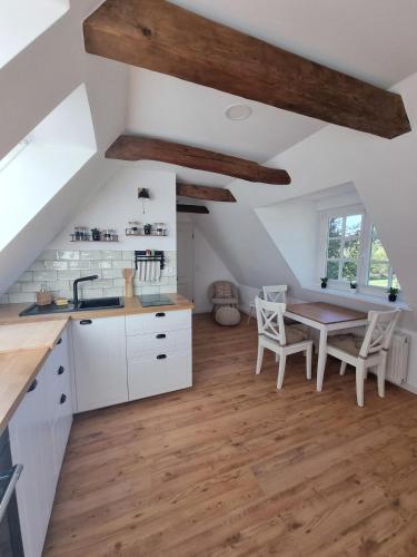 a kitchen with white cabinets and a wooden table at Lichtdurchflutete Dachgeschosswohnung mit Charme in Goldenstedt