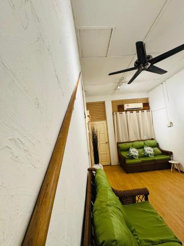 a living room with a green couch and a ceiling fan at Guesthouse 20 - Free WiFi, Netflix & snacks in Banting