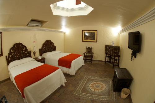 a hotel room with two beds and a television at Hotel Hacienda Vista Hermosa in Tequesquitengo