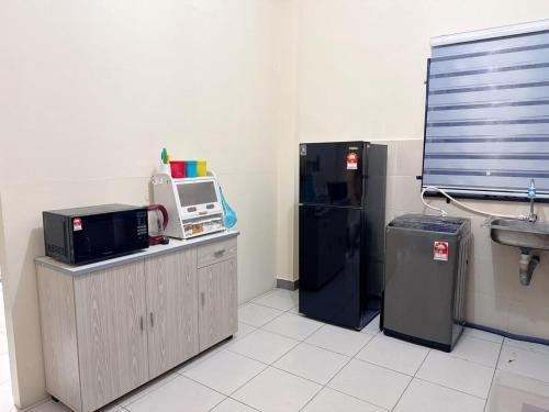 a kitchen with a refrigerator and a microwave at EQAMEL Homestay Corner Lot in Sandakan