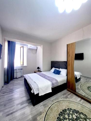 a bedroom with a large bed and a mirror at Стильная студия в центре с кухней in Bukhara