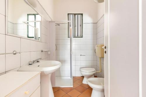 a white bathroom with a sink and a toilet at Villa Simona - Torre Lapillo in Isola della Malva