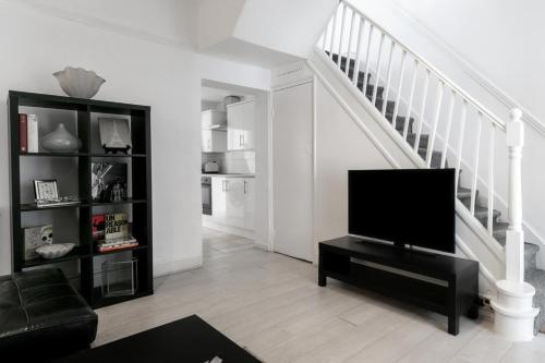 a living room with a television and a staircase at 4 Bed House - Sleeps 6 - Garden Pets Wifi in London