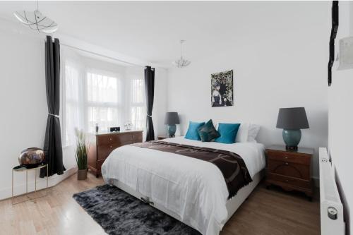 a white bedroom with a large bed with blue pillows at 4 Bed House - Sleeps 6 - Garden Pets Wifi in London