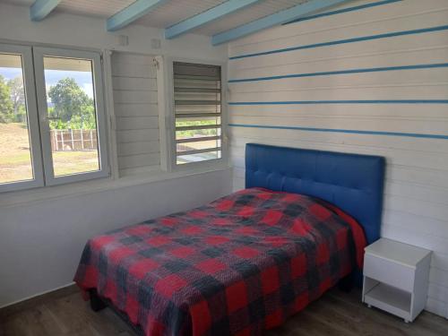 a bedroom with a blue bed in a room with windows at villa domaine des palétuviers in Le Moule