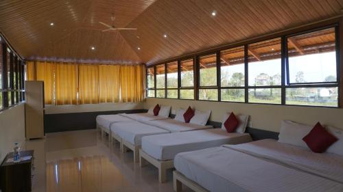 a row of beds in a room with windows at Chirooss Homestays And Resorts in Chikmagalūr